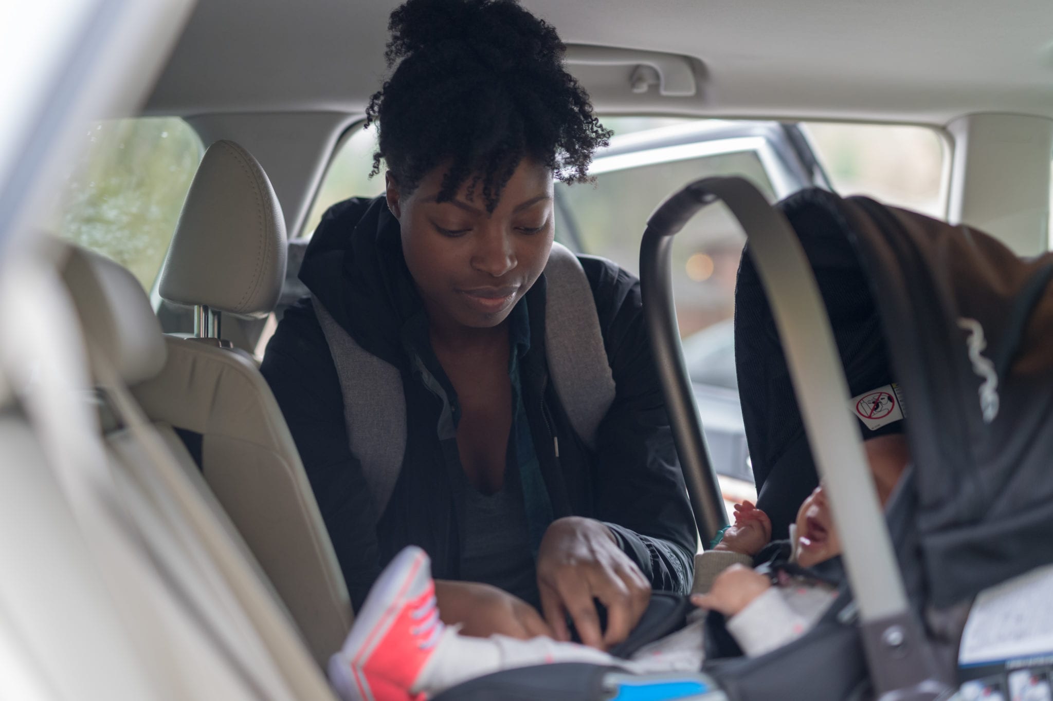 Mom puts her infant baby into the carseat