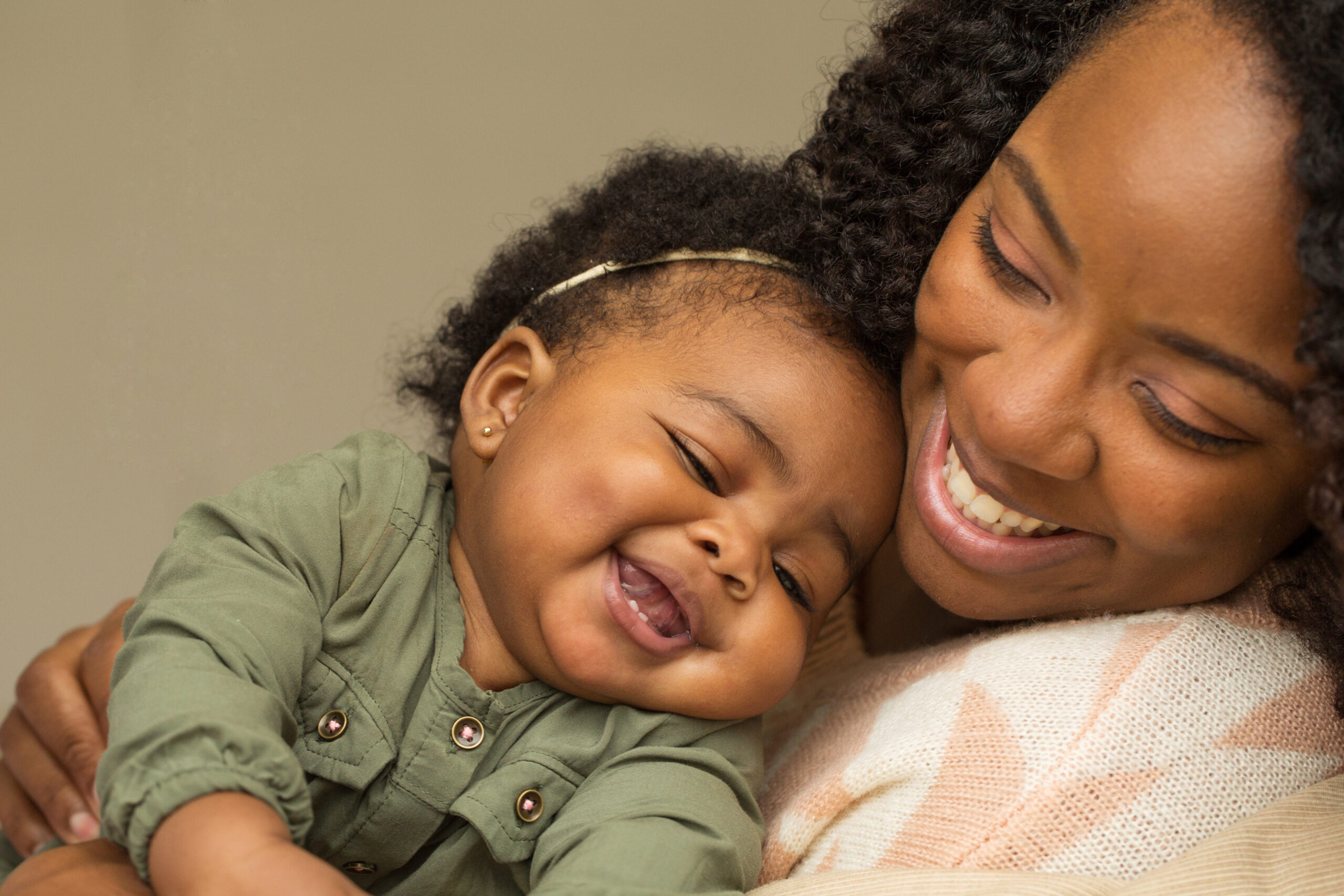 Smiling woman of color embracing her laughing baby