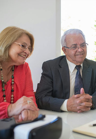 Screenshot Older couple talking with financial advisor about an IRA Charitable Rollover
